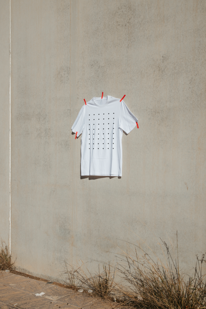 K T-Shirt 02 — Front, on wall mockup surface